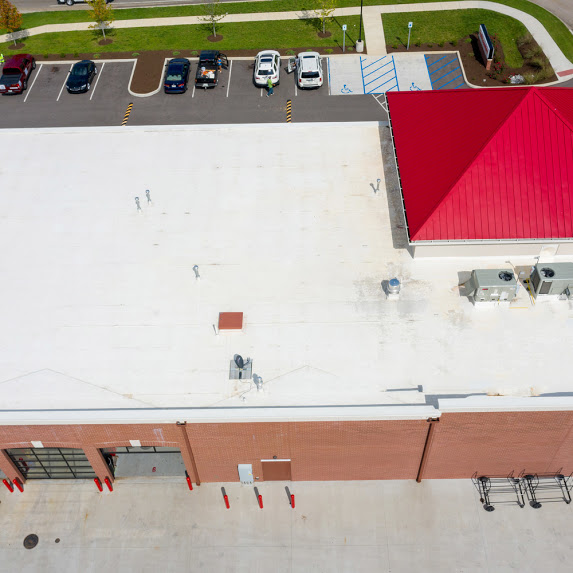 commercial flat roof with a red metal hip roof section.