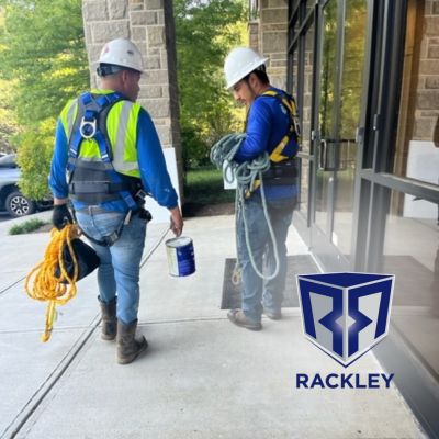 Two Rackly Roofing workers with safety gear walking beside a building